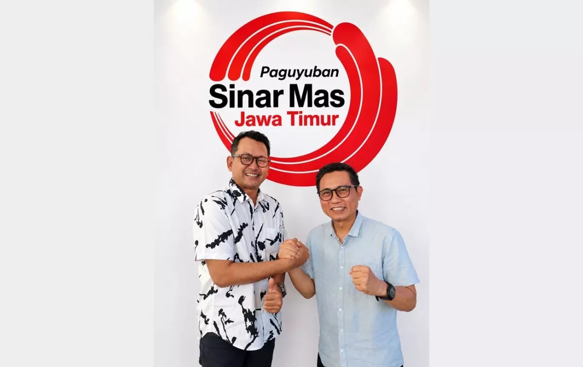 Momen keakraban Bapak Sasongko Adhi Widodo dan Bapak Dodik Ariyanto berpose salam komando di depan logo Paguyuban Sinar Mas Jawa Timur, menyimbolkan kekompakan dalam estafet kepemimpinan.